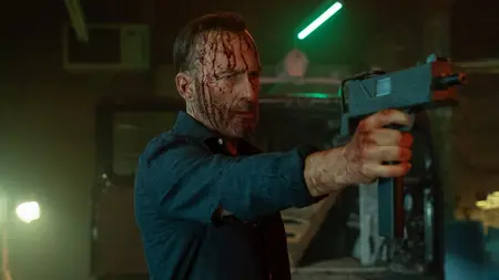 Bob Odenkirk strikes an unbothered, cool pose with blood all over his face while he also holding up an Uzi gun in the action sequel NOBODY 2.