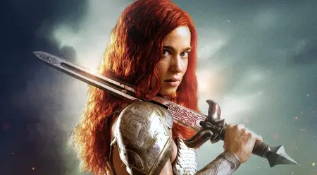 Actress Matilda Lutz stuns as the female warrior Sonja resting her large sword on the shoulder of her shiny silver armor on the official poster of the new RED SONJA remake.