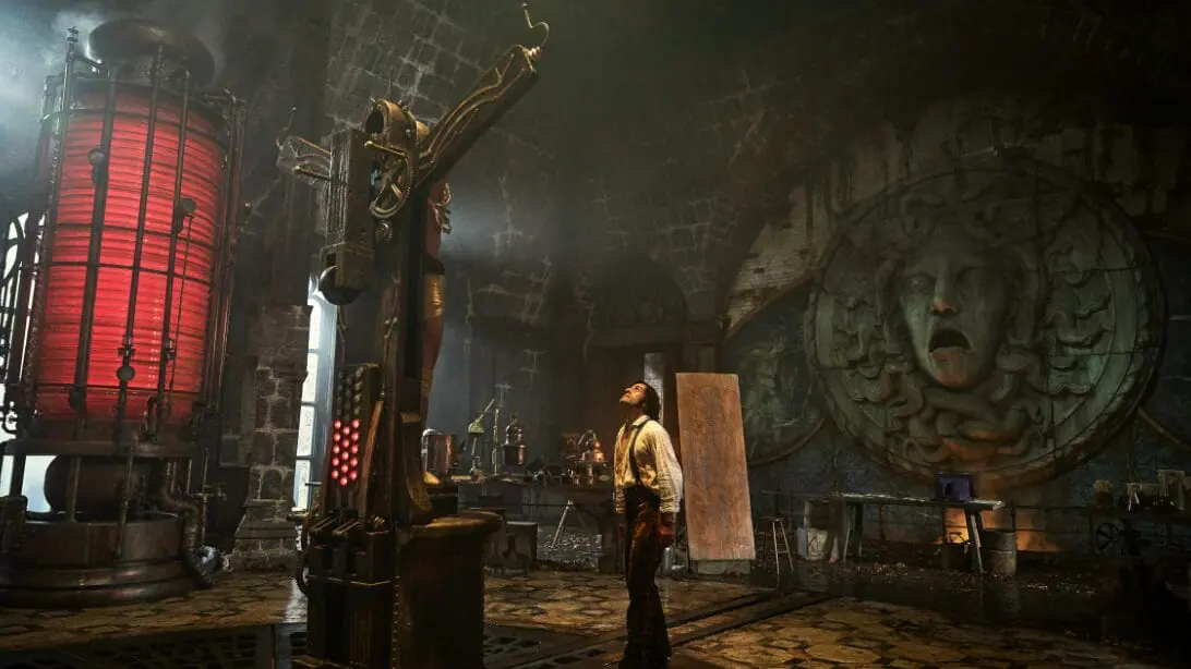 Doctor Victor Frankenstein, played by Oscar Isaac, stares up at an unseen corpse experiment whose body is crucified on a large cross in his giant, beautiful Gothic laboratory in FRANKENSTEIN directed by Guillermo del Toro.