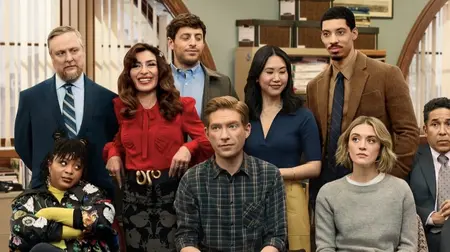 Domhnall Gleeson looks greatly annoyed as he sits in the middle of a group photo with his hilarious employees at the office of the Midwestern Toledo Truth-Teller newspaper in The Office spin-off series THE PAPER, streaming only on Peacock.