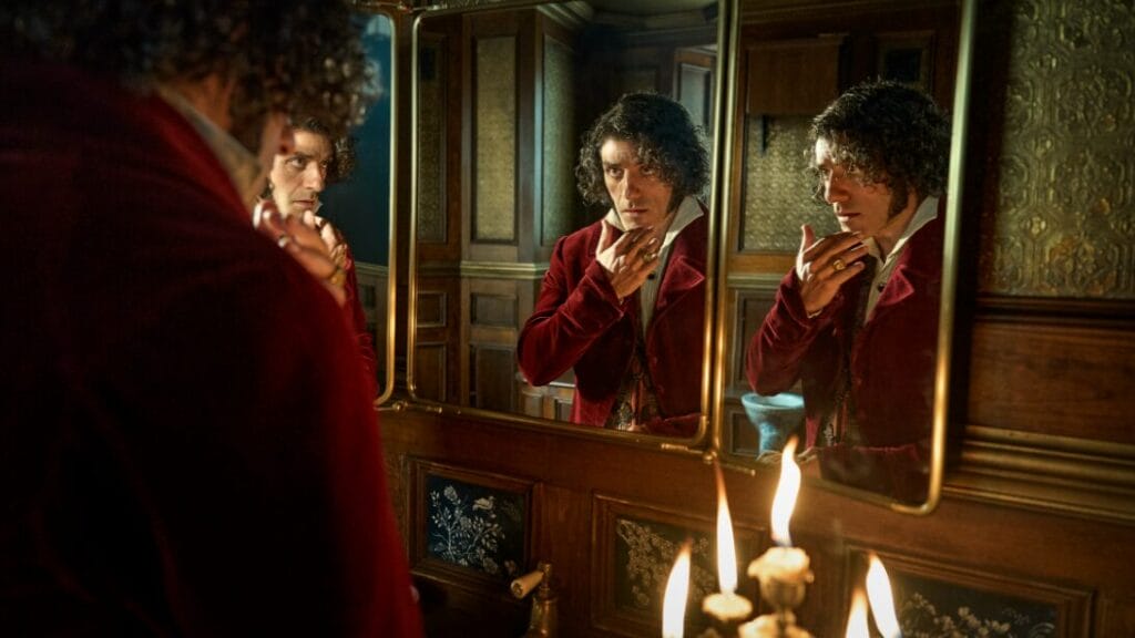 Dr. Victor Frankenstein, played by Oscar Isaac, stares into his empty soul in a large three-way mirror in his lavish bathroom from Guillermo del Toro's FRANKENSTEIN. 