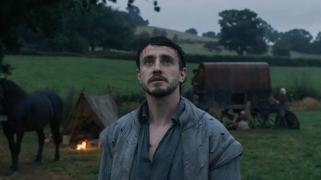 Paul Mescal stars as William Shakespeare dramatically standing in front of the desolate backdrop of a beautiful 16-century English countryside in Chloé Zhao's HAMNET film.