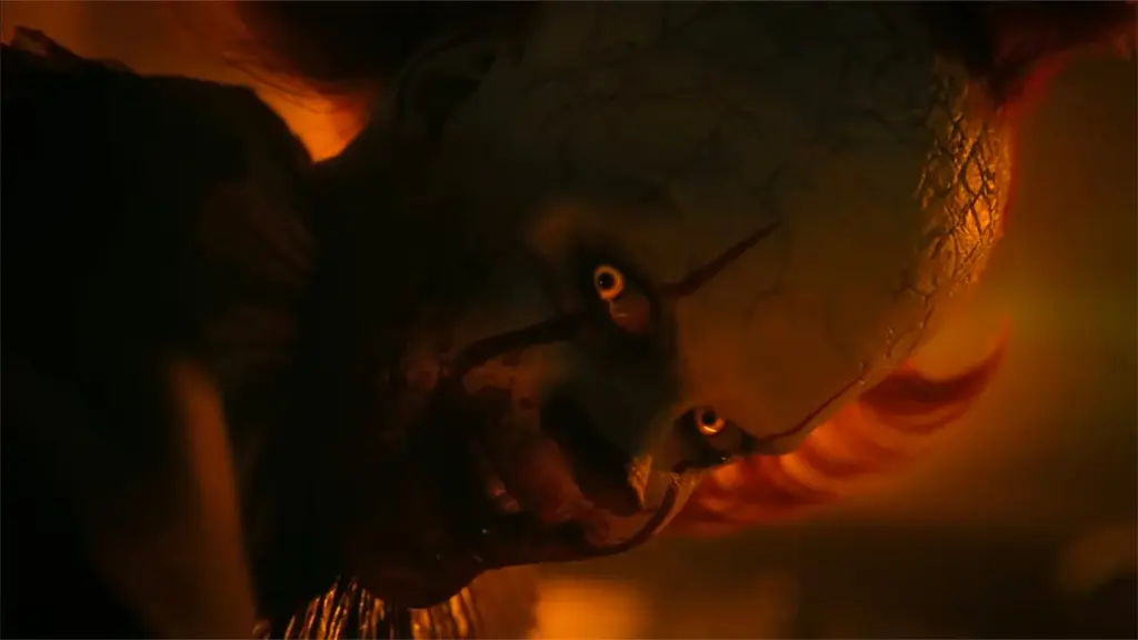 A terrifying close-up shot of Pennywise the dancing clown played by Bill Skarsgård showing off a sinister smile with his glowing yellow eyes in IT: WELCOME TO DERRY streaming only on HBO Max.