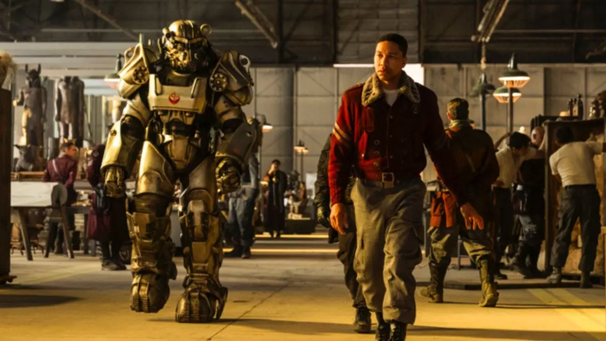 Aaron Moten as Maximus walking through a Brotherhood of Steel facility next to a fellow soldier wearing Power Armor in FALLOUT Season 2 streaming only on Prime Video.