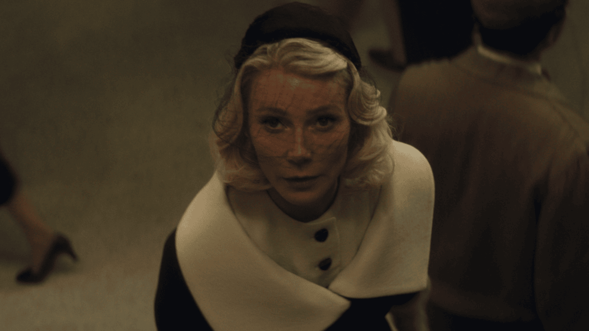 Gwyneth Paltrow stars as Old Hollywood starlet Kay Stone looking up to the camera while wearing a beautiful veil and white-collared coat in the A24 period movie MARTY SUPREME.