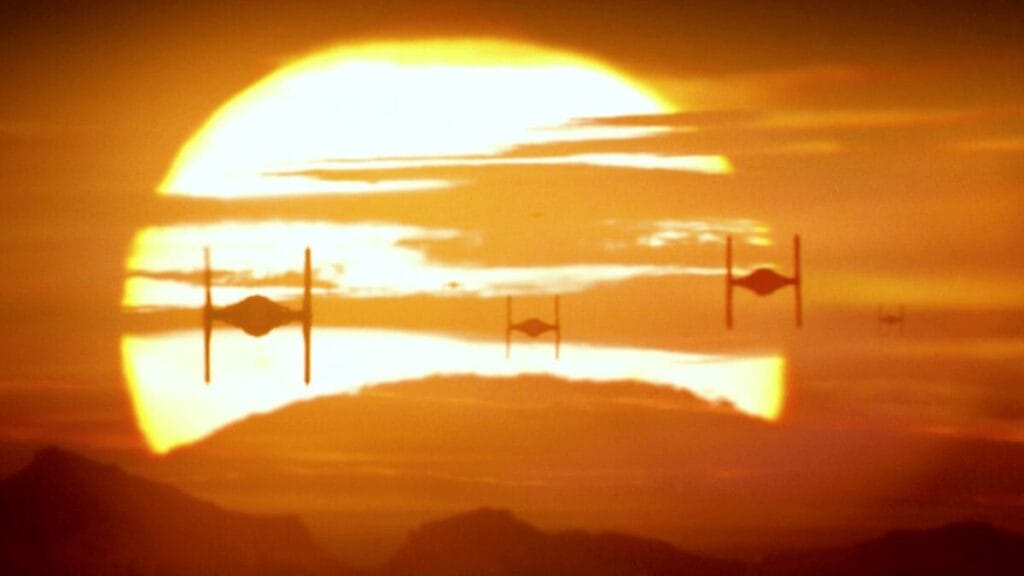 An epic shot from STAR WARS: THE FORCE AWAKENS of three TIE Fighters flying through clouds high in the sky against the backdrop of a large golden sunset, which pays homage to a similar iconic shot from Francis Ford Coppola's Apocalypse Now.