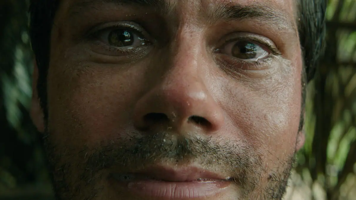 An extreme close-up shot of Dylan O'Brien's paralyzed face with tears running down his eyes in Sam Raimi's horror thriller SEND HELP. 