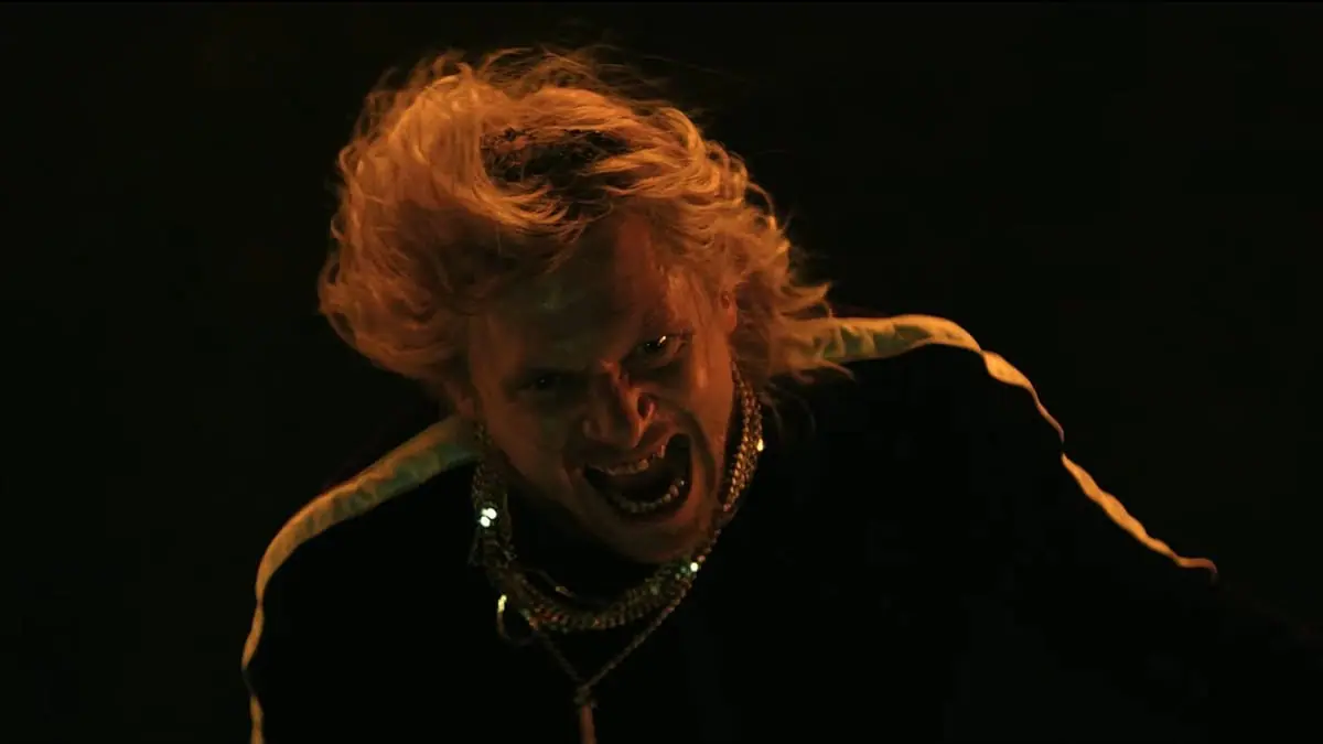 The satanic cult leader Sir Jimmy Crystal, played by Jack O'Connell, screams into the camera as his blonde wig and gold chains wave around in the horror sequel 28 YEARS LATER: THE BONE TEMPLE.