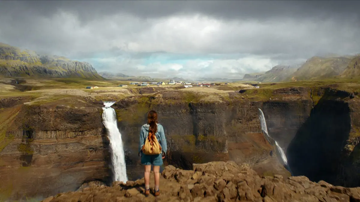 Eleven, played by Millie Bobby Brown, hikes up a mountain in Iceland to find a village in the distance nestled over 2 waterfalls in the closing moments of STRANGER THINGS Season 5.