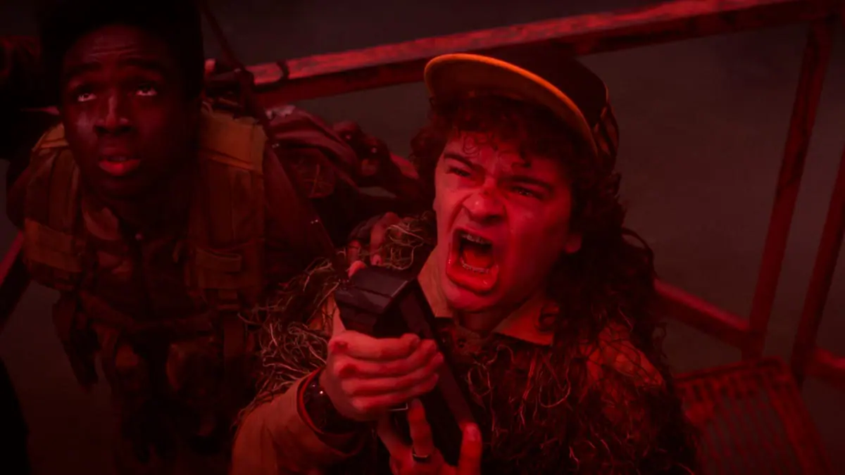 A shot of Lucas and Dustin looking up and screaming in terror in the bright neon red Upside Down from the series finale episode of STRANGER THINGS.