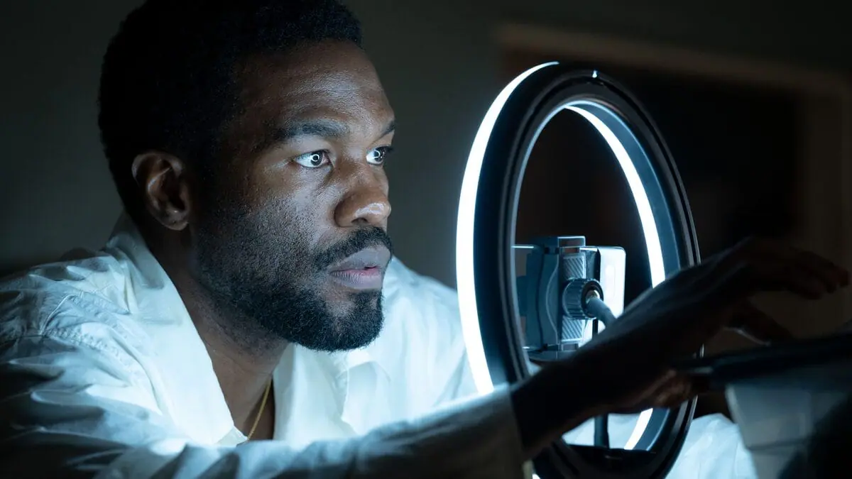 Yahya Abdul-Mateen II records an audition video of himself on his phone with a large ring light up to his face in Marvel's WONDER MAN streaming only on Disney+.