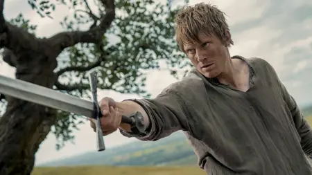 Peter Claffey stars as Ser Duncan the Tall raising his large and shiny sword towards the camera in an epic battle shot from the Game of Thrones spin-off show A KNIGHT OF THE SEVEN KINGDOMS.