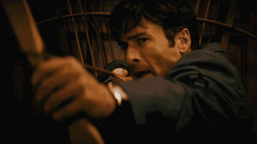 A close-up of Glen Powell preparing to shoot a bow and arrow while wearing a classy business suit in the social class thriller HOW TO MAKE A KILLING.