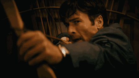 A close-up of Glen Powell preparing to shoot a bow and arrow while wearing a classy business suit in the social class thriller HOW TO MAKE A KILLING.