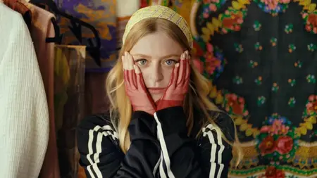 Anna Baryshnikov stars as the young Russian fashion designer Margarita Levlansky holding her hands up to her face and making a scared face while recording an audition tape for a reality show in the satirical comedy IDIOTKA.