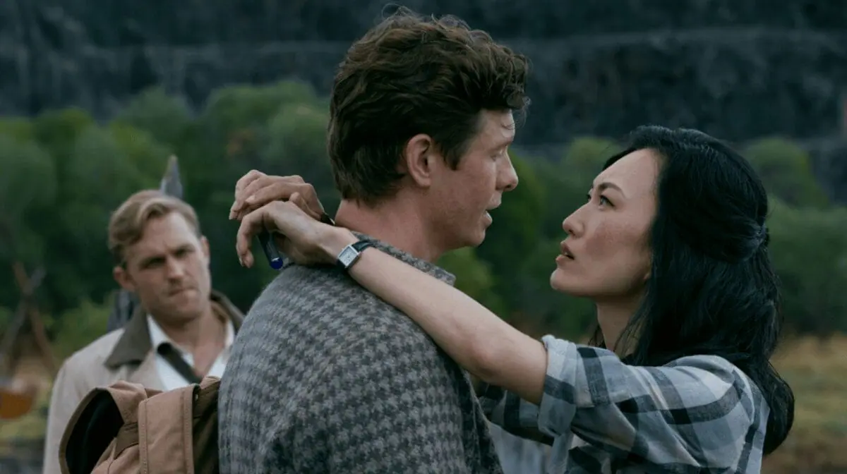 Keiko Miura embraces Bill Randa with an intimate hug as Lee Shaw watches them from behind, forming a love triangle in the 1950s storyline of MONARCH: LEGACY OF MONSTERS Season 2. 