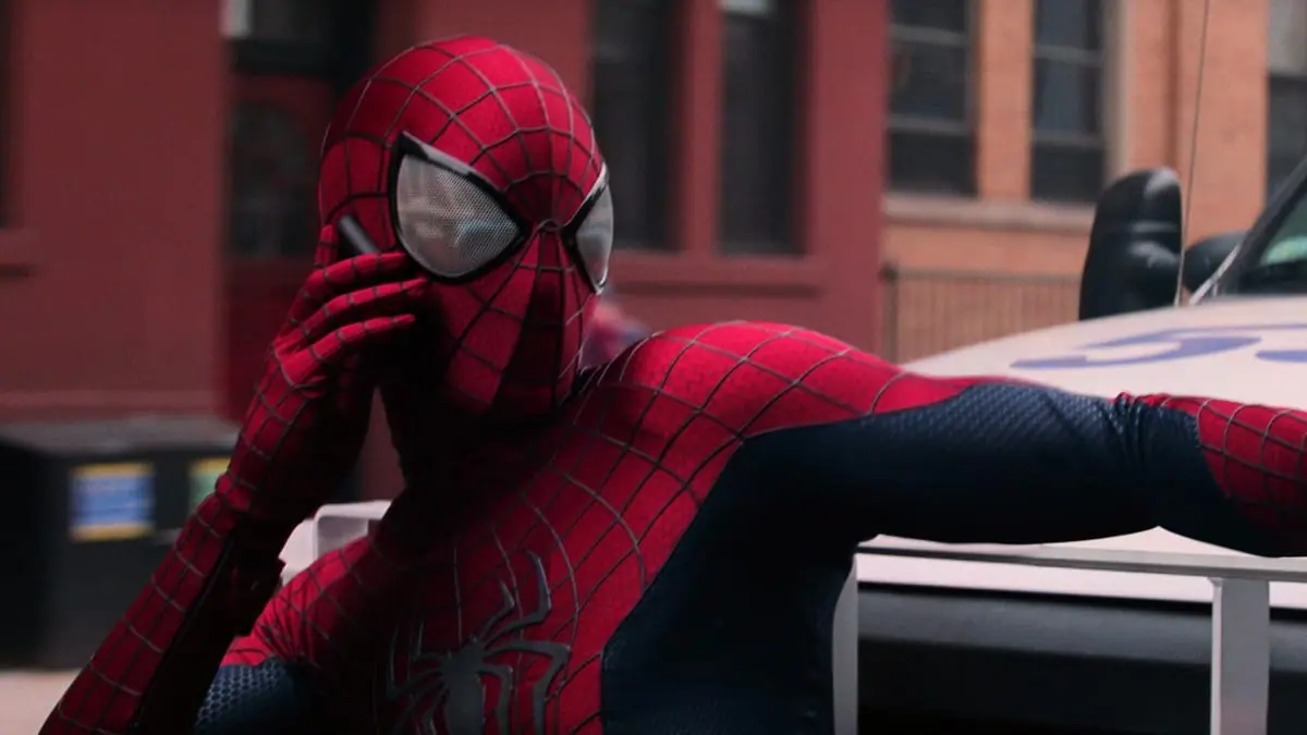 Spider-Man, played by Andrew Garfield, answers the phone while hanging onto the front side of a large truck during the opening chance sequence of THE AMAZING SPIDER-MAN 2. 