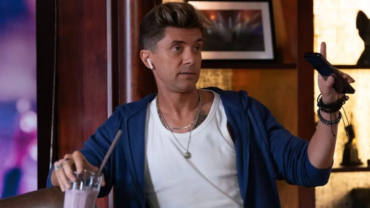 Actor Topher Grace shows off a douchey haircut and obnoxious spray tan look while drinking a purple smoothie in the dark comedy thriller HOW TO MAKE A KILLING. 