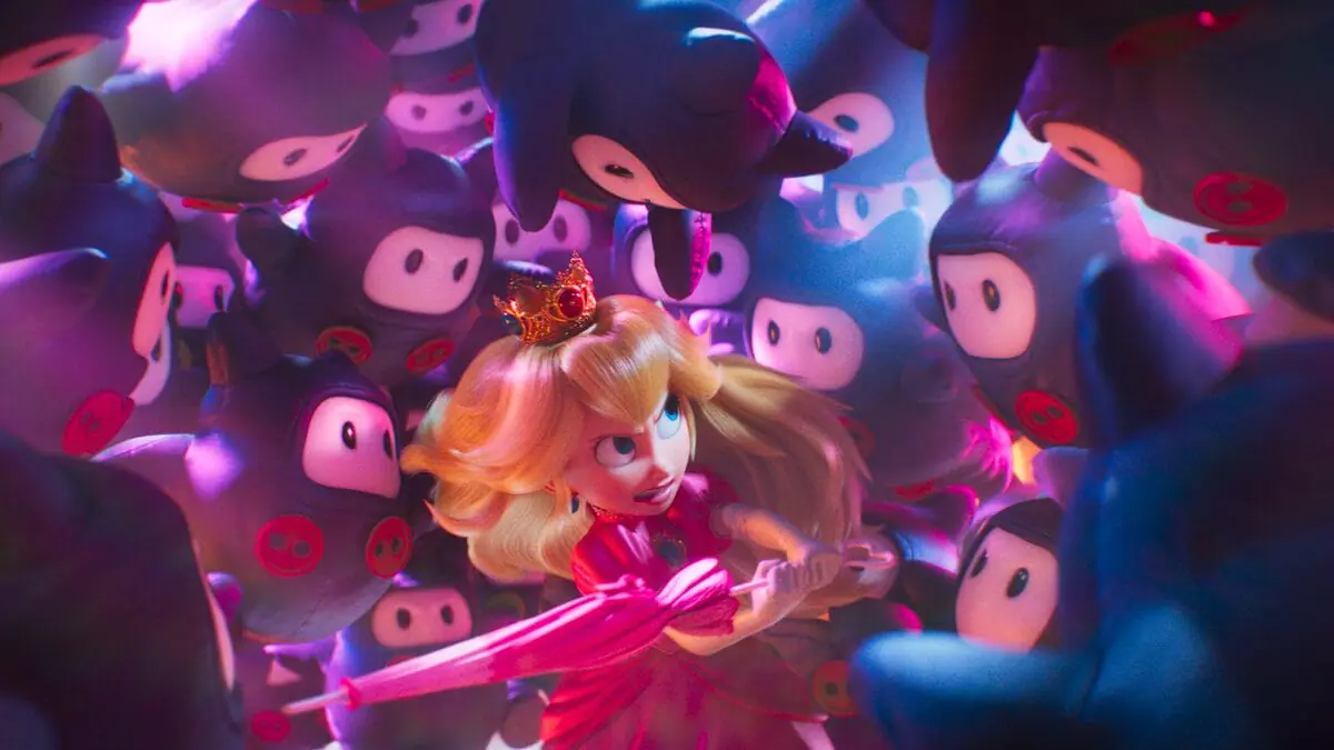 An epic shot of Princess Peach swinging her iconic pink umbrella while being swarmed by a giant group of attacking cute Ninjis in THE SUPER MARIO GALAXY MOVIE. 