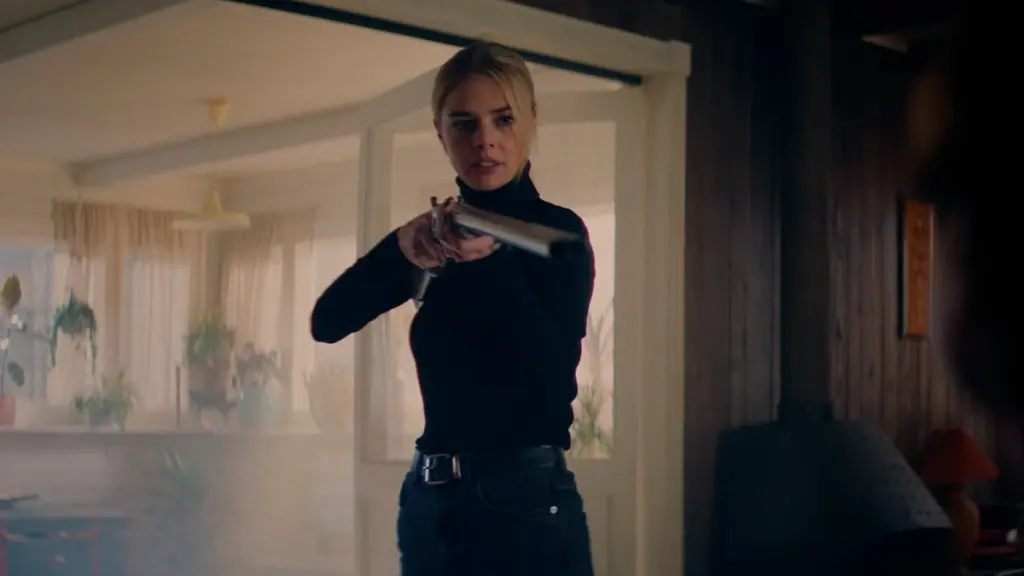 Actress Samara Weaving strikes an awesome pose while wielding a shotgun in the action comedy OVER YOUR DEAD BODY. 