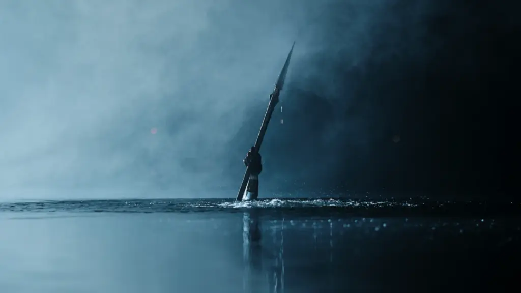 A sinister hand holding a large spear rises above the murky waters of a dark lake in the Slasher homage film TEENAGE SEX AND DEATH AT CAMP MIASMA.