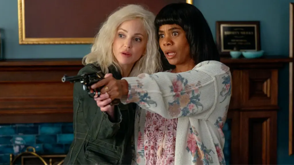 Anna Faris looking like an old Laurie Strode with white hair aims a gun with Regina Hall dressed up as Ma in Scary Movie 6. 