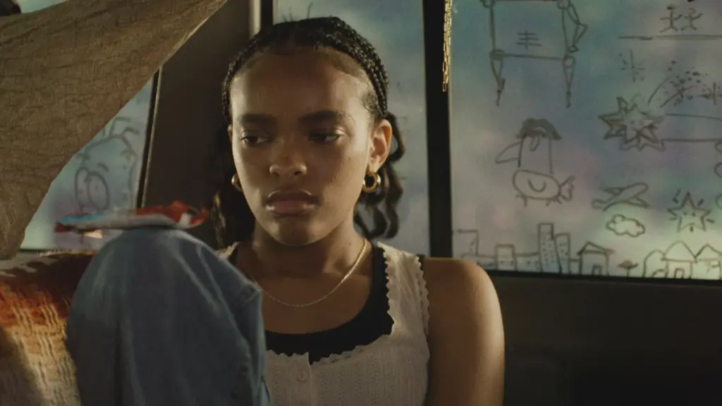 Akira Jackson stars as the character Day sitting in a car with a bunch of figures and symbols drawn on the dusty windows from the indie horror movie IT ENDS.