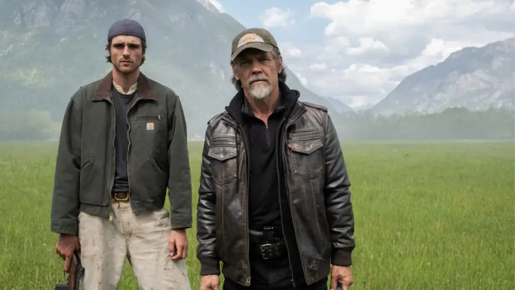 Josh Brolin and Jacob Elordi stand in the middle of a beautiful green field while wearing tactical gear in the post-apocalyptic thriller THE DOG STARS. 