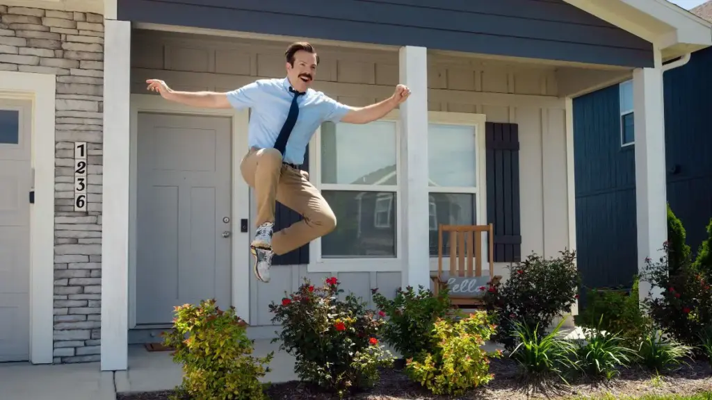 A funny freeze frame of Jason Sudeikis jumping up high with a look of joy and happiness from the premiere episode of TED LASSO Season 4. 