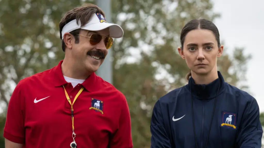 Jason Sudeikis and Tanya Reynolds make hilarious faces as they try to tolerate each other in TED LASSO Season 4 on Apple TV. 